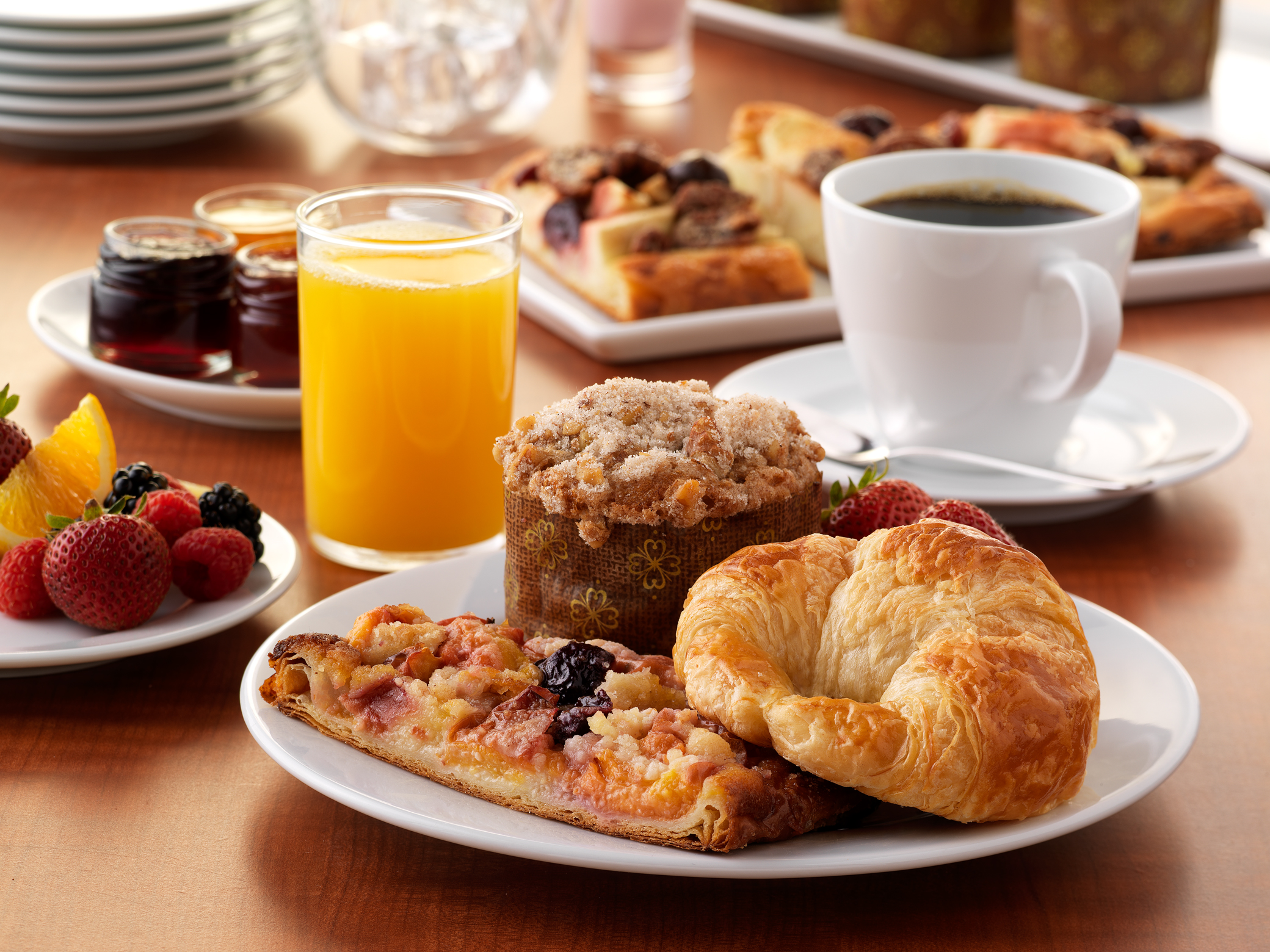 mesa com refeições matinais como pães, torradas, um copo com suco, uma xícara com café representando o café da manhã pelo mundo