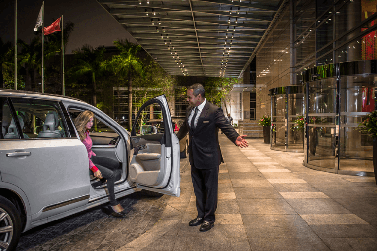 funcionário do hotel recebendo o hospede segurando a porta do carro