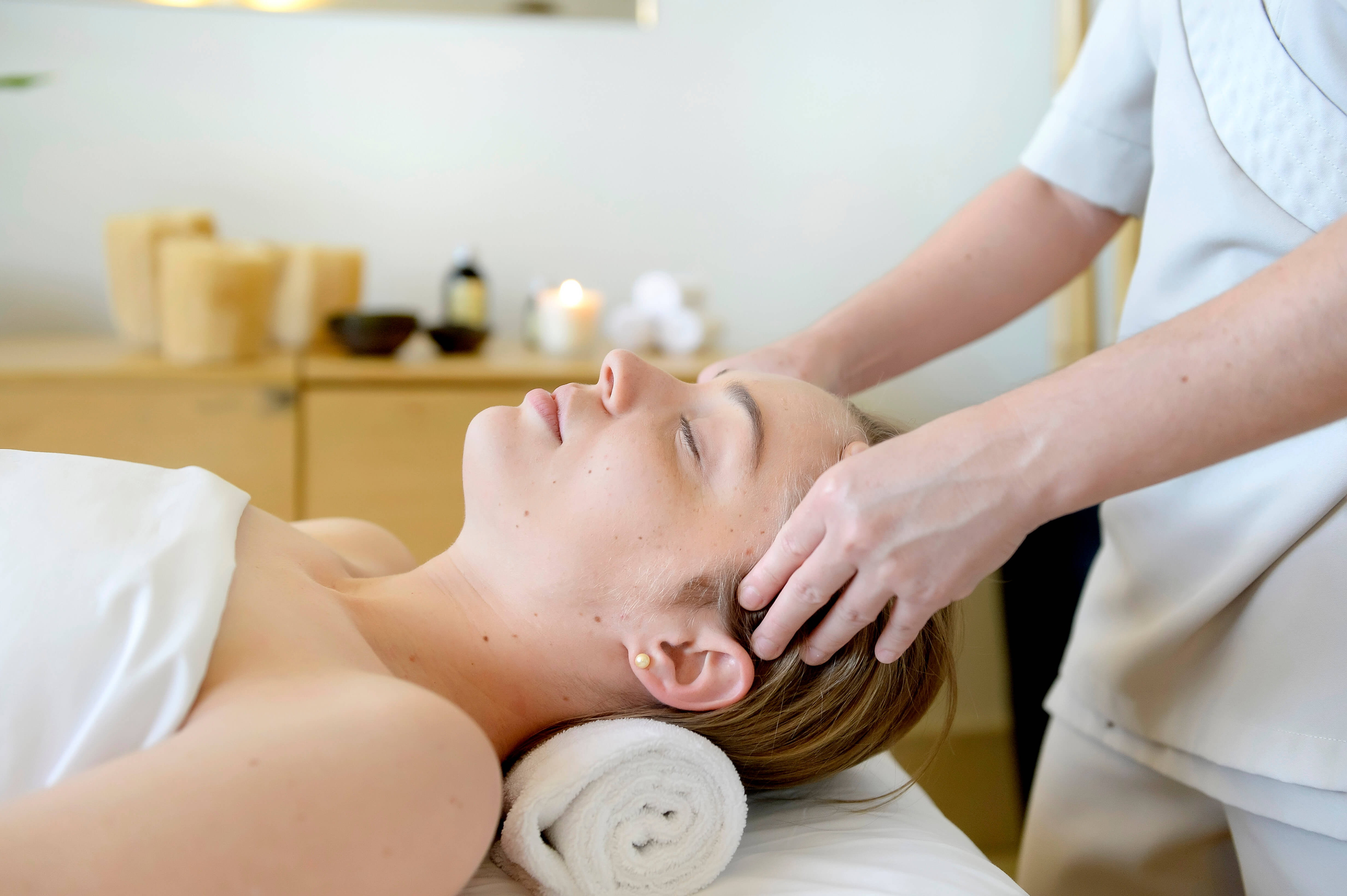 tratamento facial cliente sendo massageada na cabeça por uma profissional