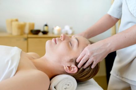 Mulher deitada recebendo massagem no rosto