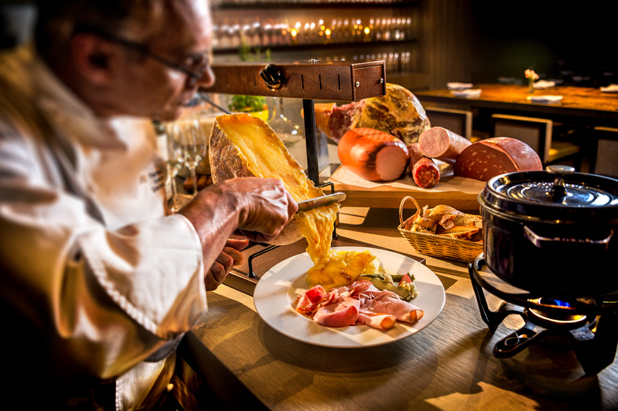 Cozinheiro servindo queijo raclette