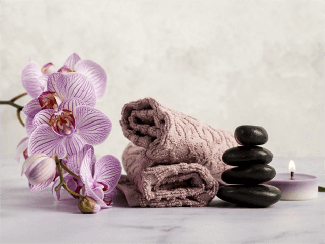 Flores, pedras quentes e toalha no spa para relaxar,