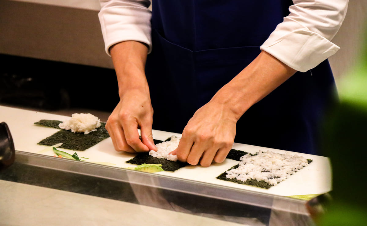 mãos de um sushiman preparando pratos como omakase