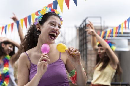 moça com maquiagem, roupa e acessórios típicos do carnaval dançando entre outras pessoas