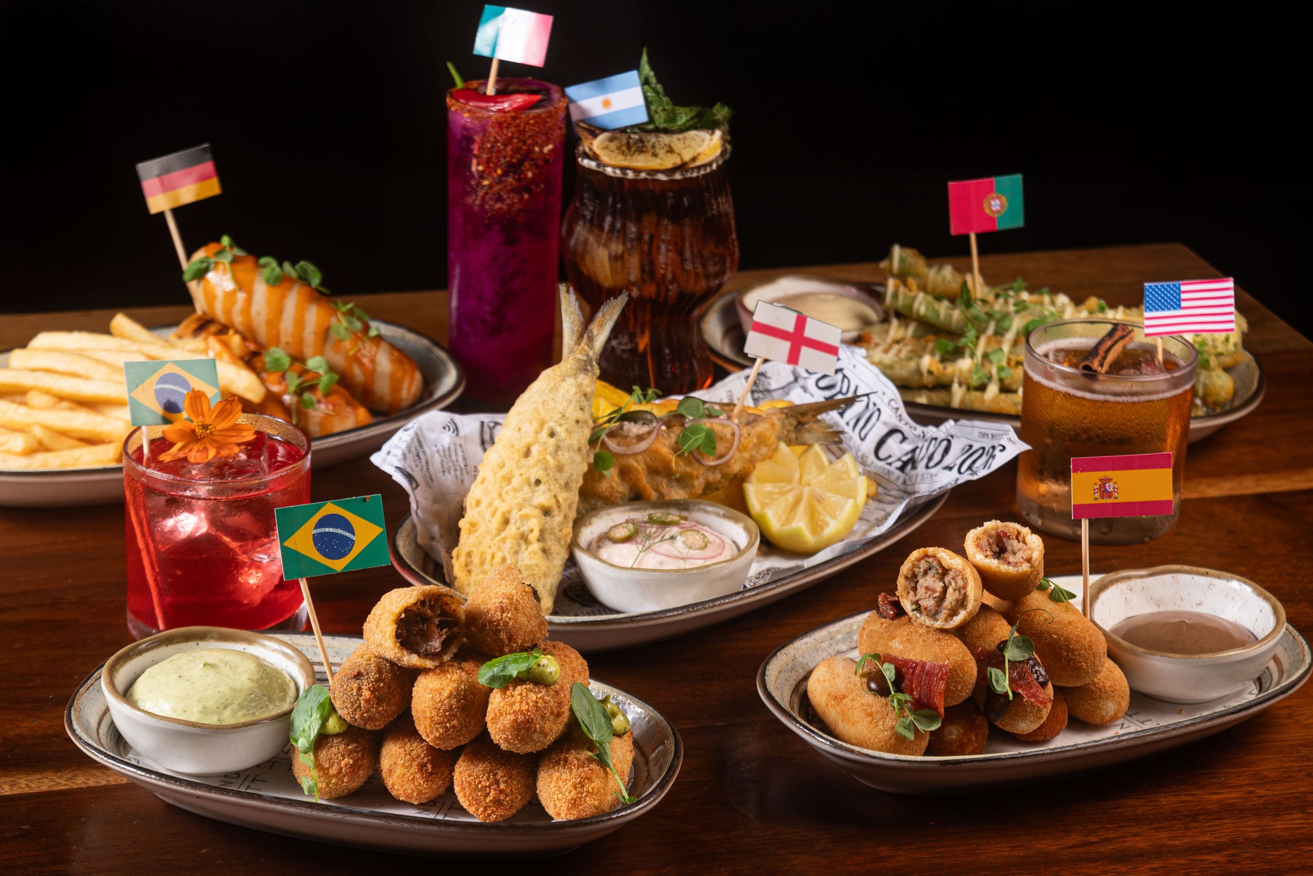 Mesa com petiscos e drinks temáticos com bandeiras de países