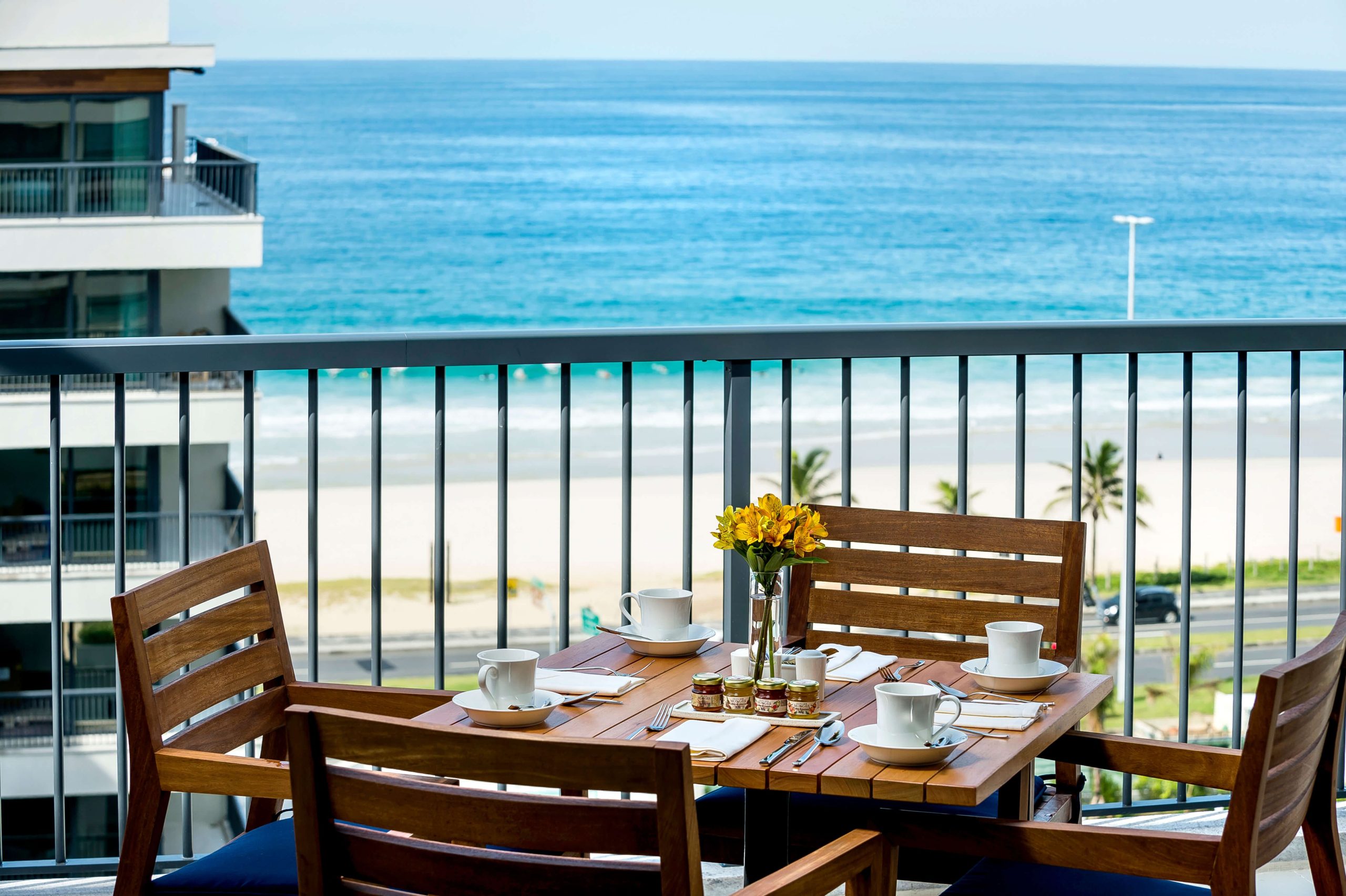 Café da manhã posto na mesa em varanda com vista para a praia.