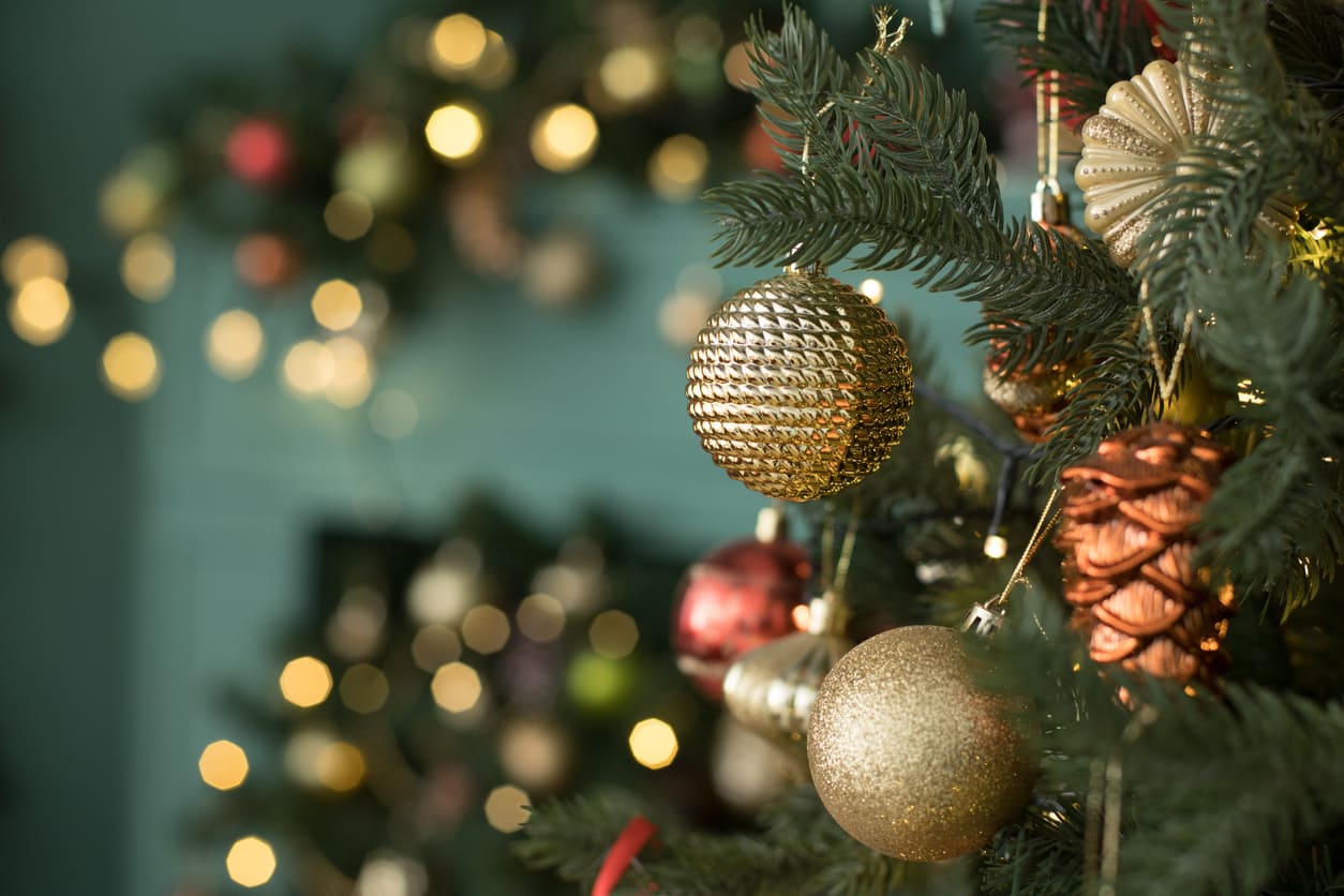 Enfeites na árvore de Natal cercada por luzes festivas.